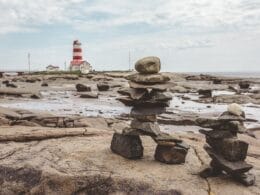 Inukshuk on the seashore near a lighthouse