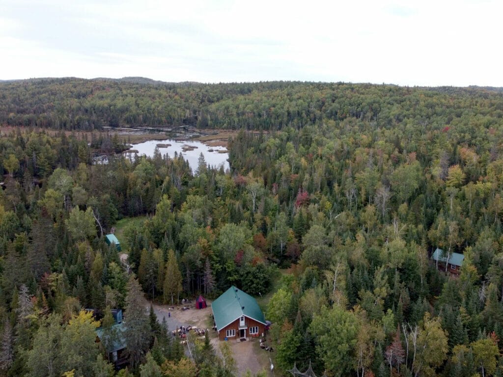 Aerial view of the reception pavilion, forest and water features of the Héritage Carcajou recreotouristic park.